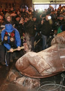 A man holds a sledgehammer as he smashes a statue of Soviet state founder Vladimir Lenin, which was toppled by protesters during a rally organized by supporters of EU integration in Kiev